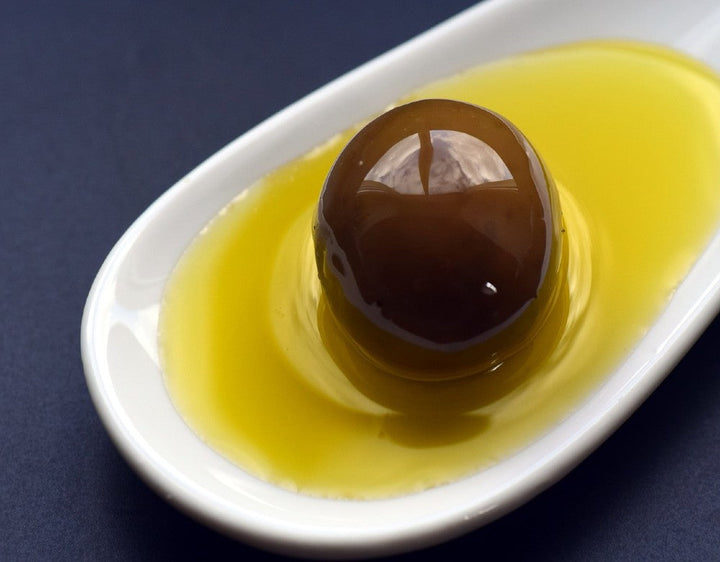 Olive in a dish of olive oil - discussing olive oil acidity