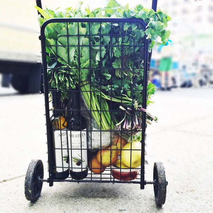 Arlotta Food Studio's olive oils in the bottom of a granny cart filled with fresh fruits and vegetables at a NY farmer's market