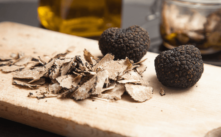 black truffles on wooden board with truffle produces and truffle oil in the background